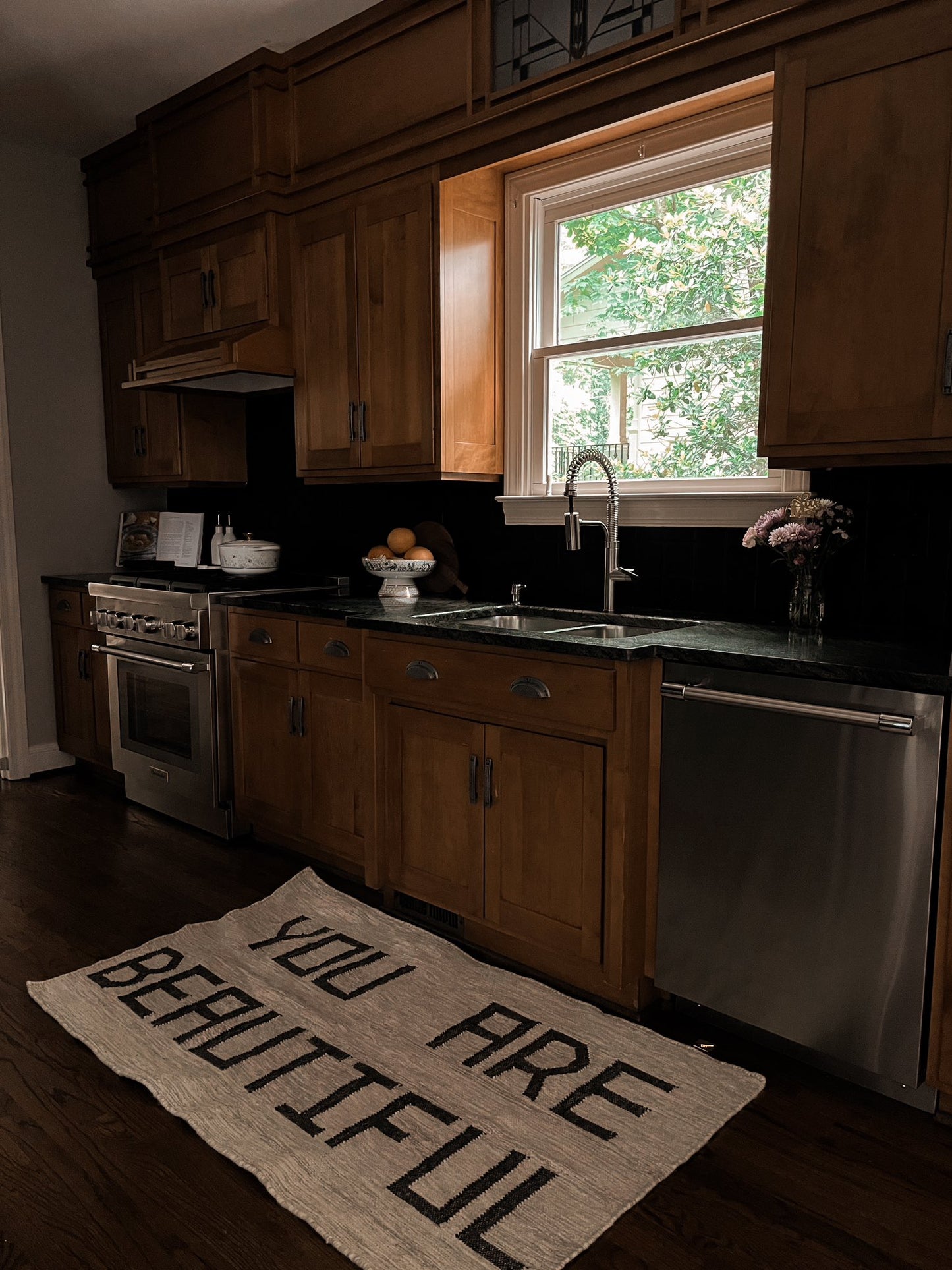 A rustic wooden farmhouse theme kitchen very elegant with modern appliances featuring a You are Beautiful bespoke and unique hand made wool rug flat weave