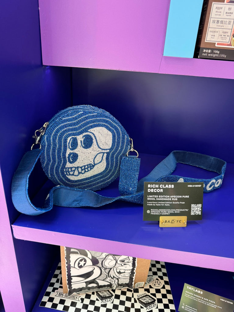 Round bejewelled Apecoin purse in blue and white, handcrafted with Beads and crystal detailing, displayed on a purple background with branded Rich Class Decor tag.
