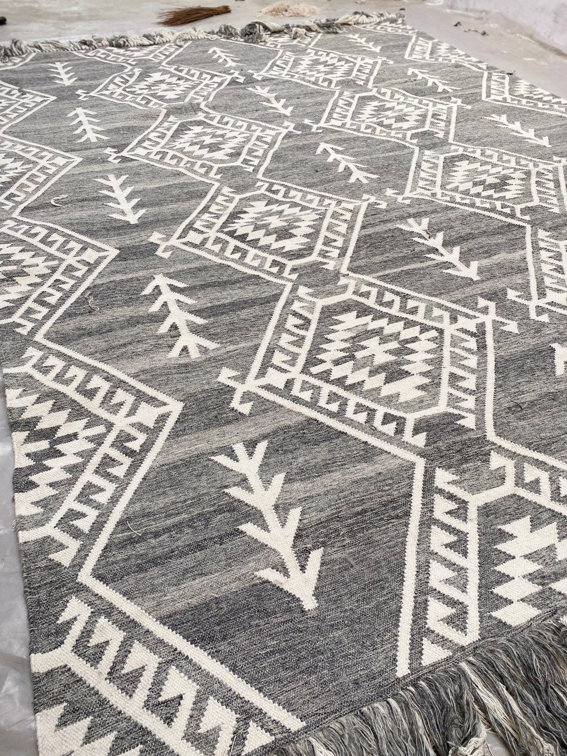 Handwoven Moroccan wool rug featuring intricate geometric patterns in neutral gray and ivory tones. This bohemian tribal area rug adds warmth, texture, and artisanal charm to any modern or rustic interior. Ethically crafted with premium materials for durability and style.