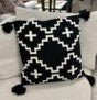 A organic cotton knitted pillow with 4 fringes on each side on the ivory sofa