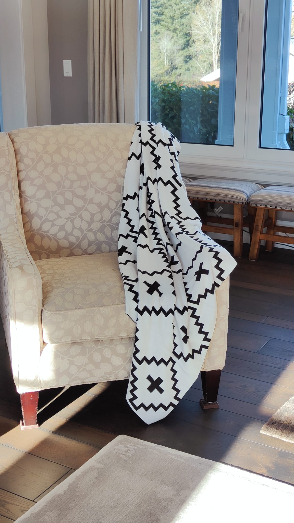 Faith Organic Cotton Throw Blanket with Free Matching Pillow – Elegant black and white geometric throw draped over a vintage armchair in a sunlit living room. Made from 100% organic cotton, perfect for cozy farmhouse, modern, and boho home décor. Limited-time offer: Free matching pillow included!