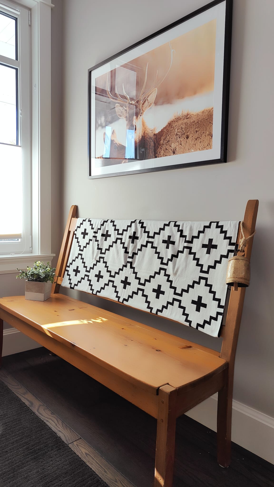 Faith Organic Cotton Throw Blanket – Black and white geometric patterned throw draped over a wooden bench in a cozy, sunlit corner. Made from 100% organic cotton, soft and breathable, perfect for farmhouse, rustic, and Scandinavian home décor.