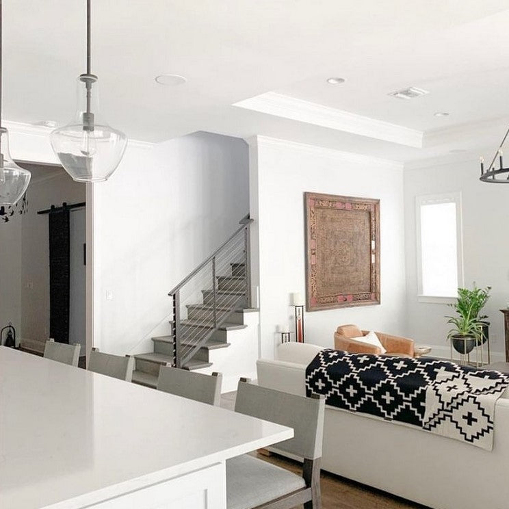 Modern open-concept living room featuring the Faith Organic Cotton Throw Blanket in black and white geometric design draped over a white sofa. A stylish and cozy addition to contemporary and bohemian home décor. Free matching pillow included for a limited time.
