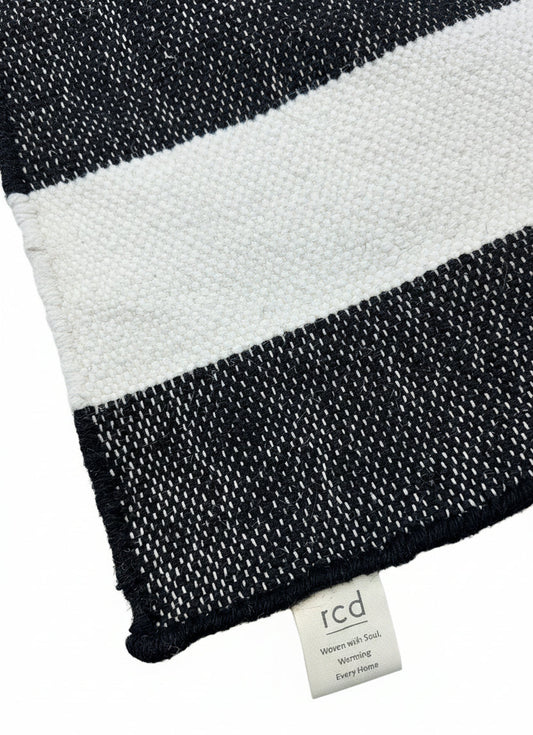 Black and white striped fabric with a brand label on a wooden surface