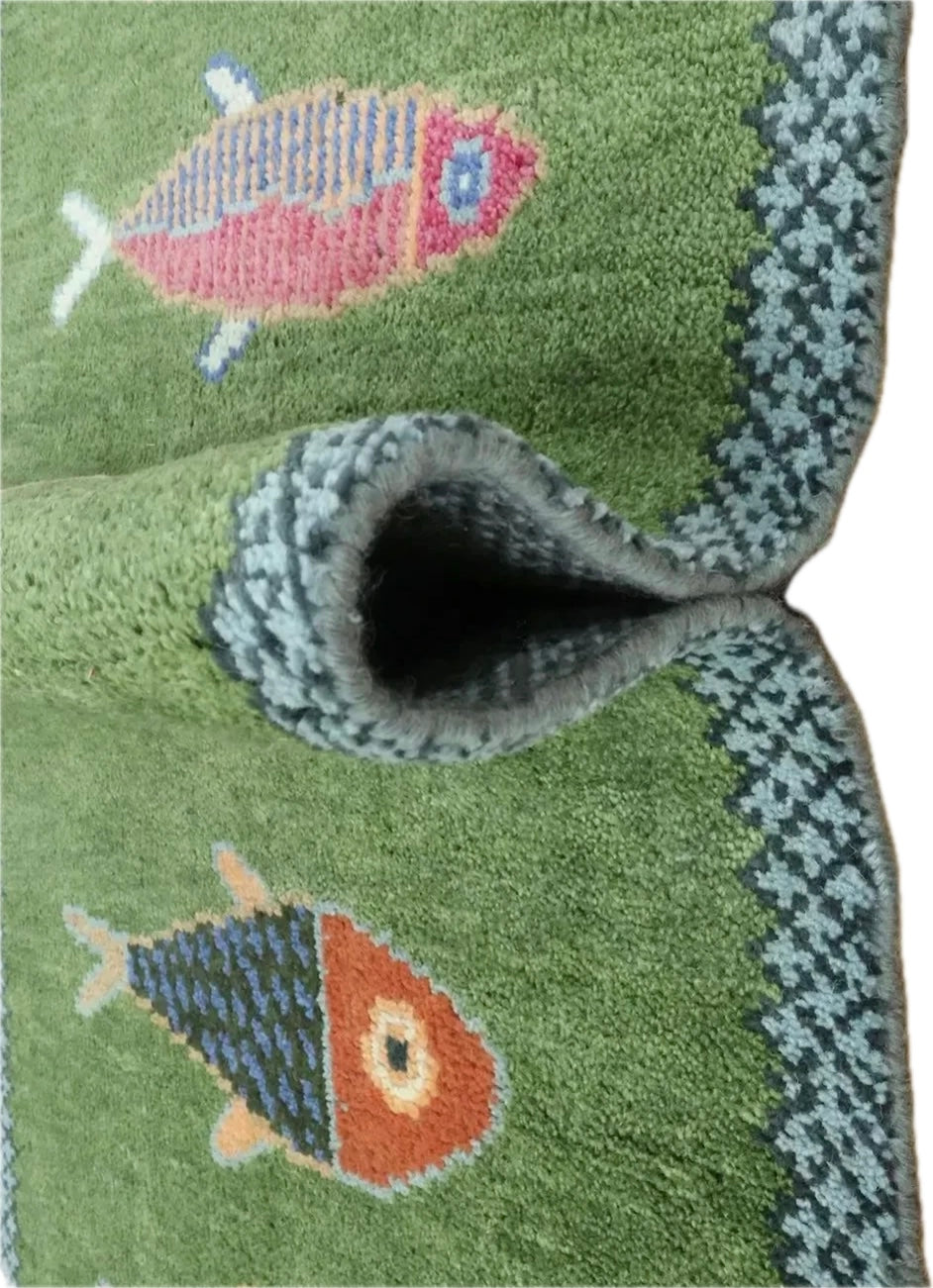 A close-up of a green textured rug featuring two stylized fish motifs and a patterned border, shown folded to reveal the pile and underside. viral koi fish runner rug