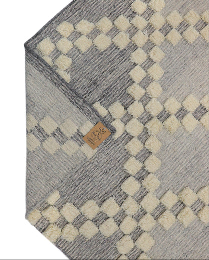 Gray and beige patterned rug with a rich class decor brand tag on a light gray background